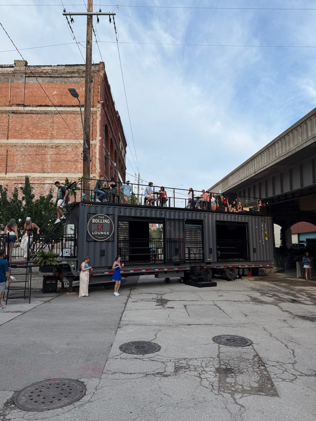 The lounge parked in an urban lot with people socializing on the rooftop