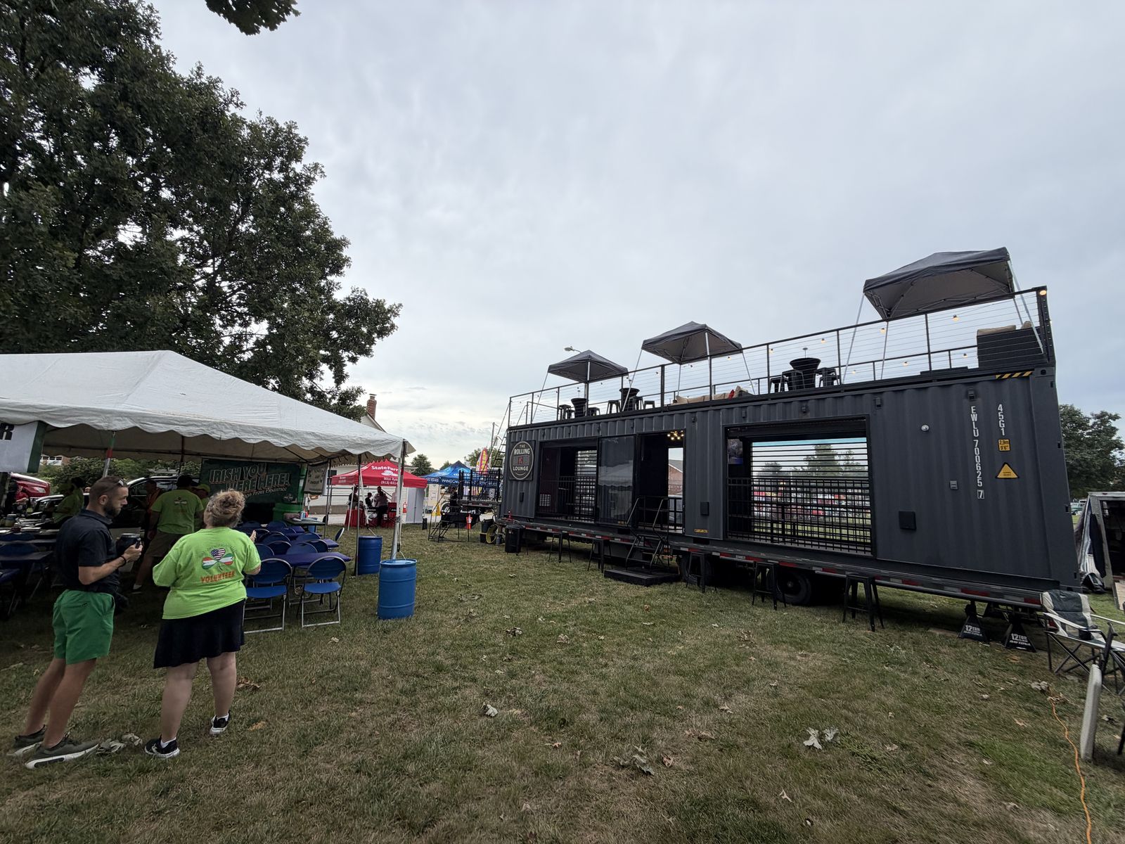 The Rolling Lounge parked on the grass at the Shawnee car show with guests on the rooftop
