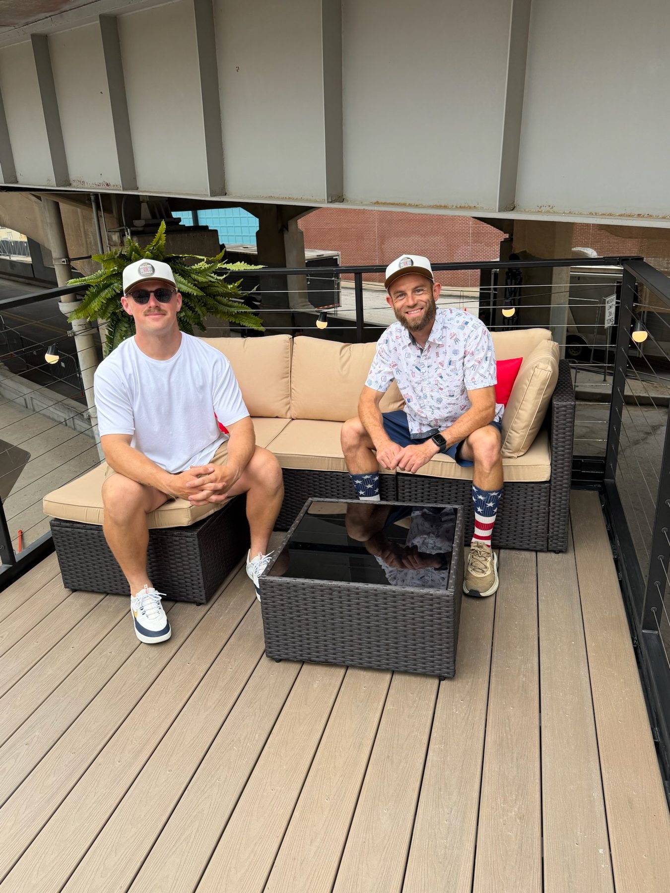Two guests smiling on the lounge rooftop sofa during a Fourth of July gathering