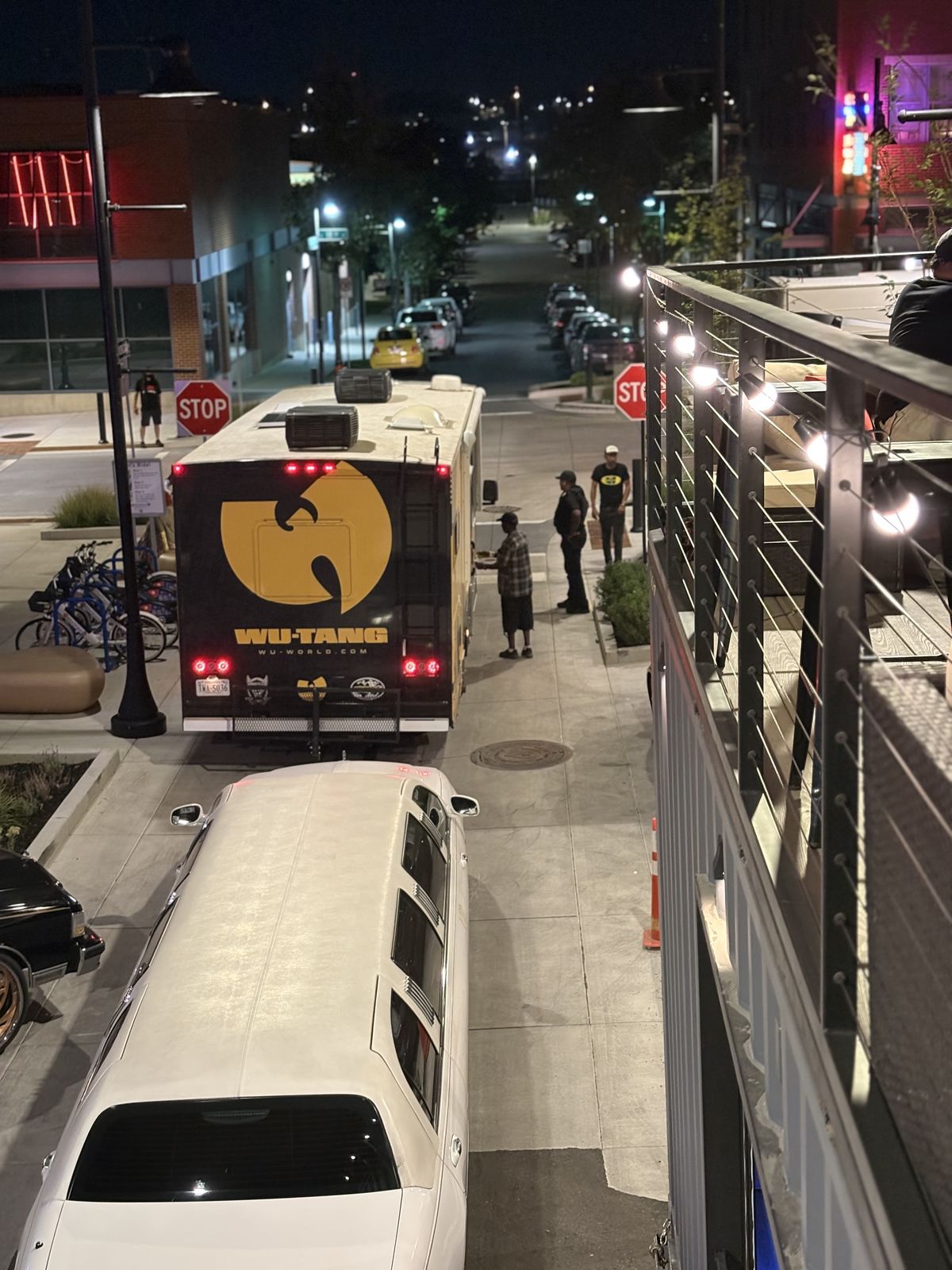 The Wu-Tang tour bus and a limo parked alongside the Rolling Lounge at night