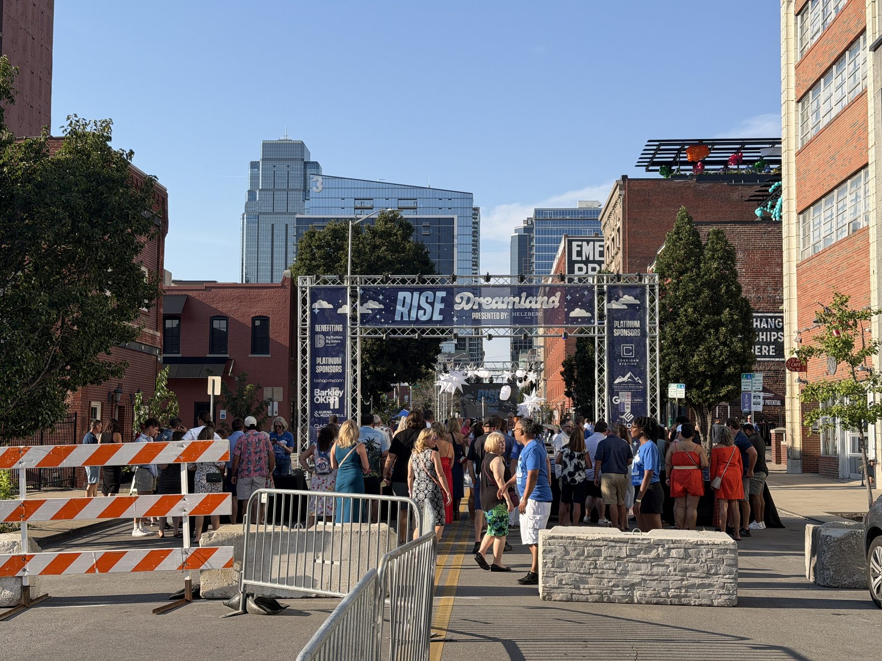 A downtown crowd at the Rise street festival with city buildings behind the entrance gate