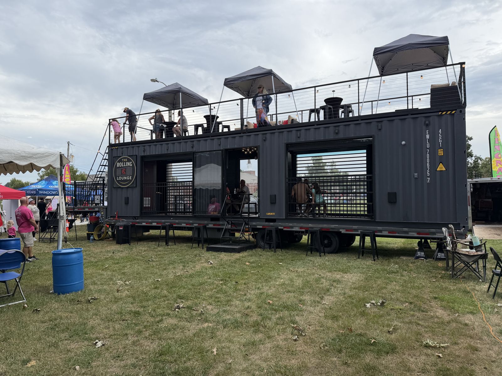 The Rolling Lounge with rooftop canopies and guests overlooking the Shawnee car show field