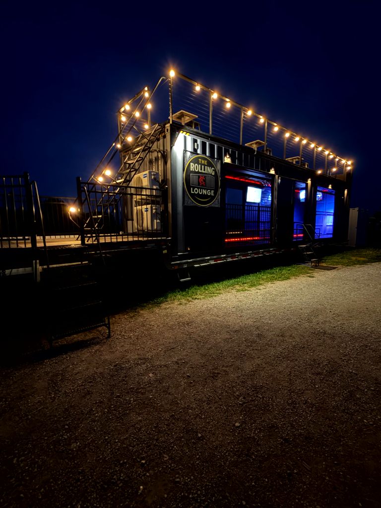 Exterior night angle of The Rolling Lounge KC with lit signage and open bays