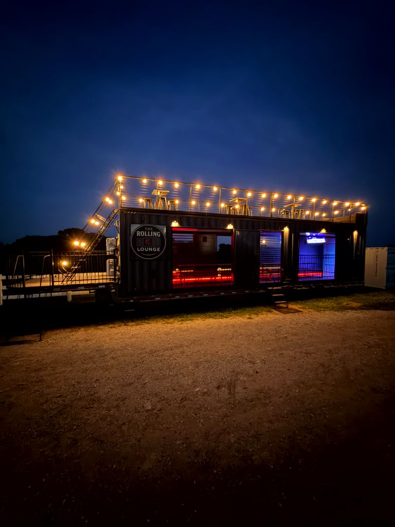 The Rolling Lounge KC glowing at night with rooftop lights and illuminated interior