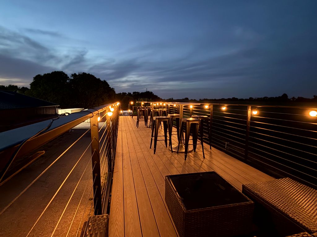 Side rooftop perspective with stools and string lights at night